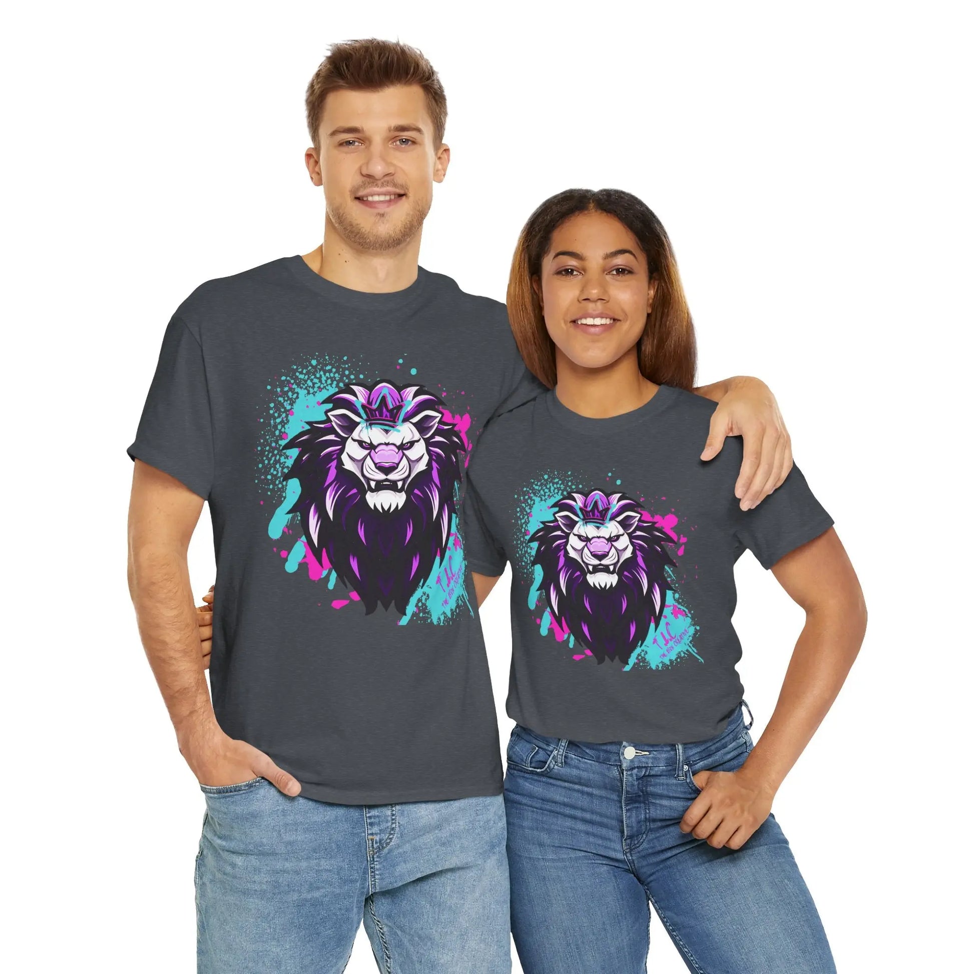 Two people are smiling and standing close together, wearing matching "The Lyon T-shirt" made of 100% cotton in dark gray, featuring a colorful abstract lion design. The classic fit tees are paired with blue jeans, showcasing the sustainable production behind each detailed thread against a white background.