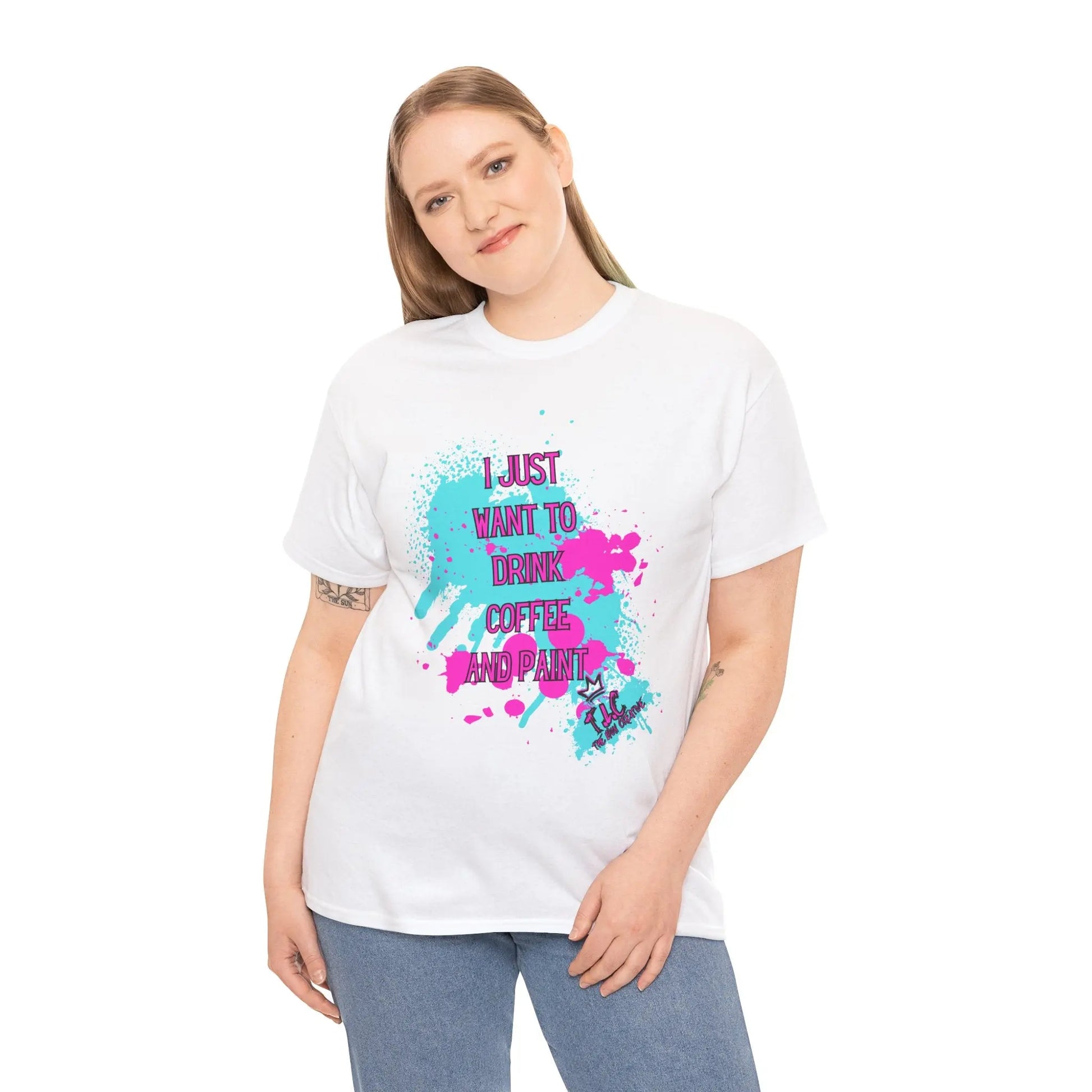 A person wearing the "I Just Want to Drink Coffee T-shirt," a classic fit cotton shirt decorated with colorful paint splatters and text, stands against a white background with a relaxed expression.