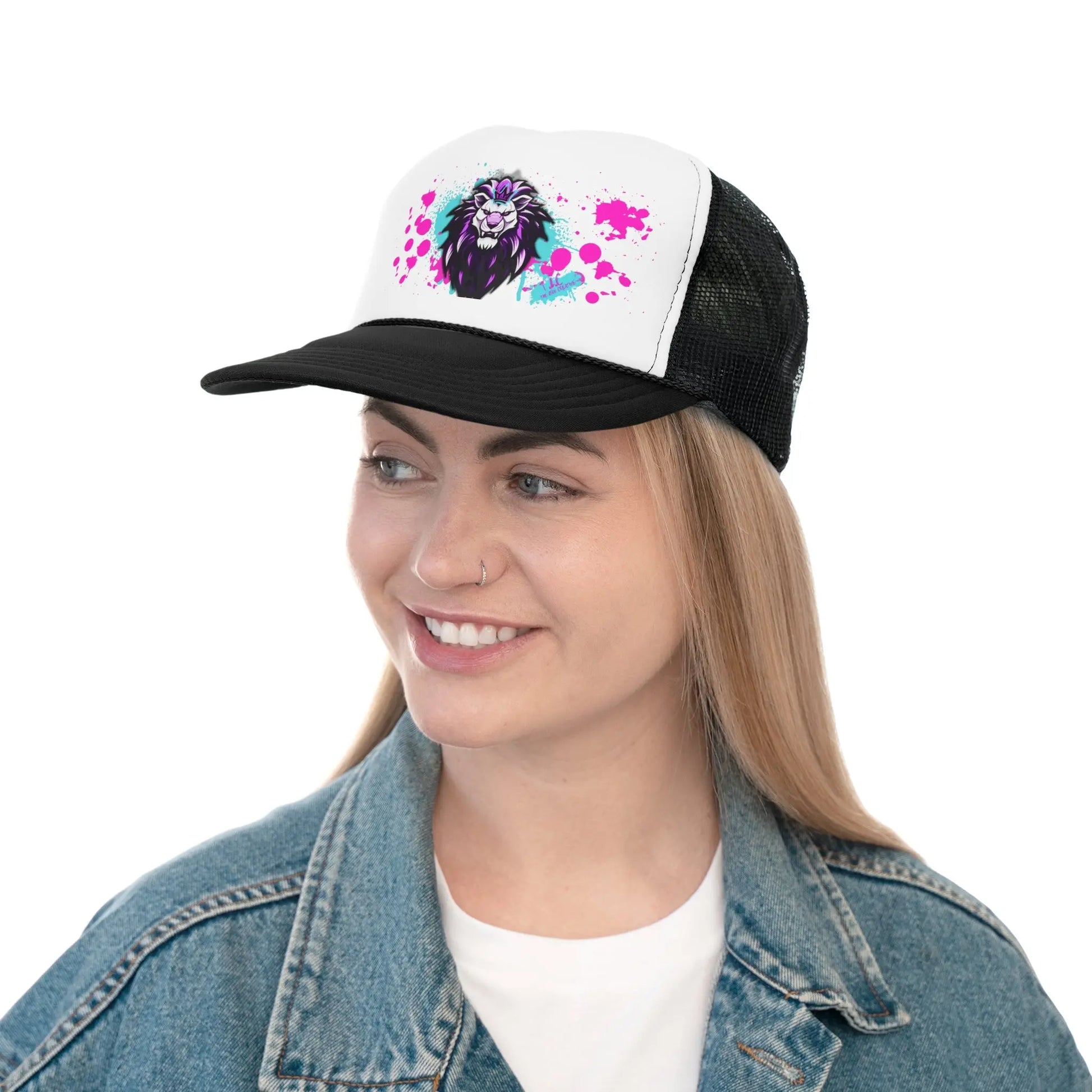 A person with long, straight hair and a nose piercing is smiling and sporting one of our Trucker Caps. The black and white cap showcases a vibrant image of a lion's face with splashes of pink and purple. They complement the cap perfectly with a light blue denim jacket and a white top, embracing the adjustable snap closure style.