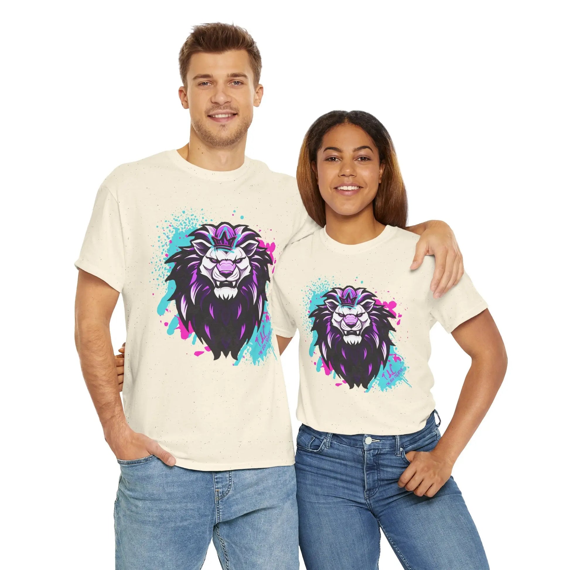 A smiling man and woman stand side by side, each wearing The Lyon T-shirt, a matching cream-colored tee made from 100% cotton. The shirts feature a vibrant lion graphic in shades of purple, blue, and black. Their classic fit complements jeans perfectly as the woman wraps her arm around the man's shoulder.