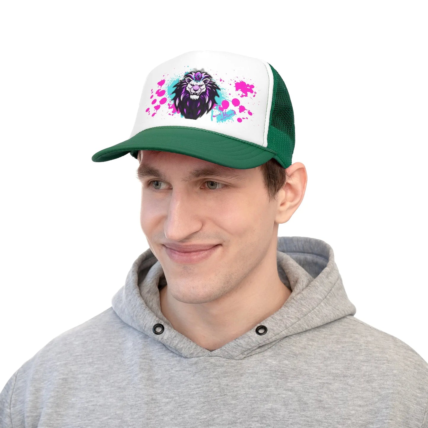 A person wearing a green and white Trucker Cap with a vibrant lion graphic on the polyester foam front. They are dressed in a light gray hoodie and are smiling slightly, looking off to the side, against a plain white background. The cap includes an adjustable snap closure for comfort.