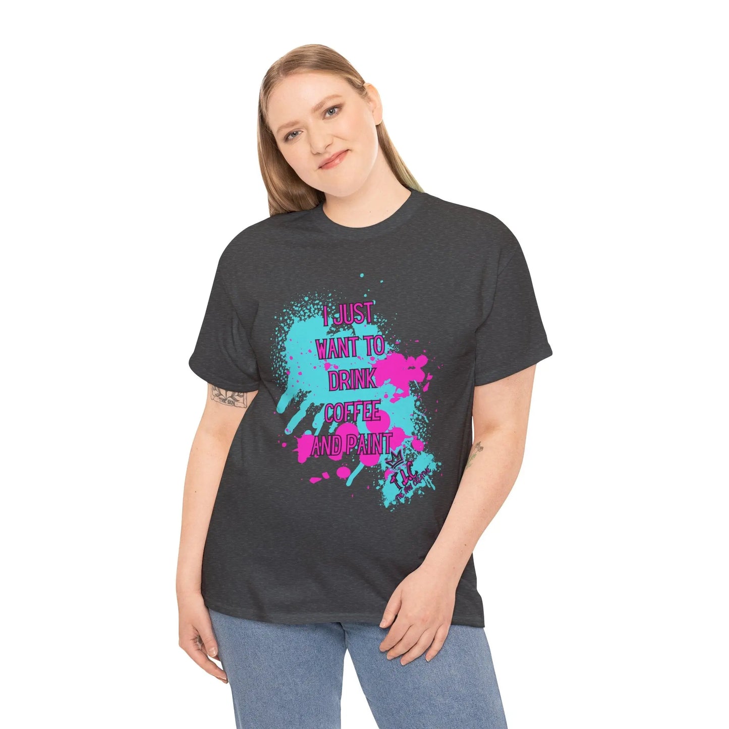 A person with long hair is wearing the classic fit "I Just Want to Drink Coffee" T-shirt, featuring colorful splashes and the text "I just want to drink coffee and paint." They stand against a plain white background, smiling softly.