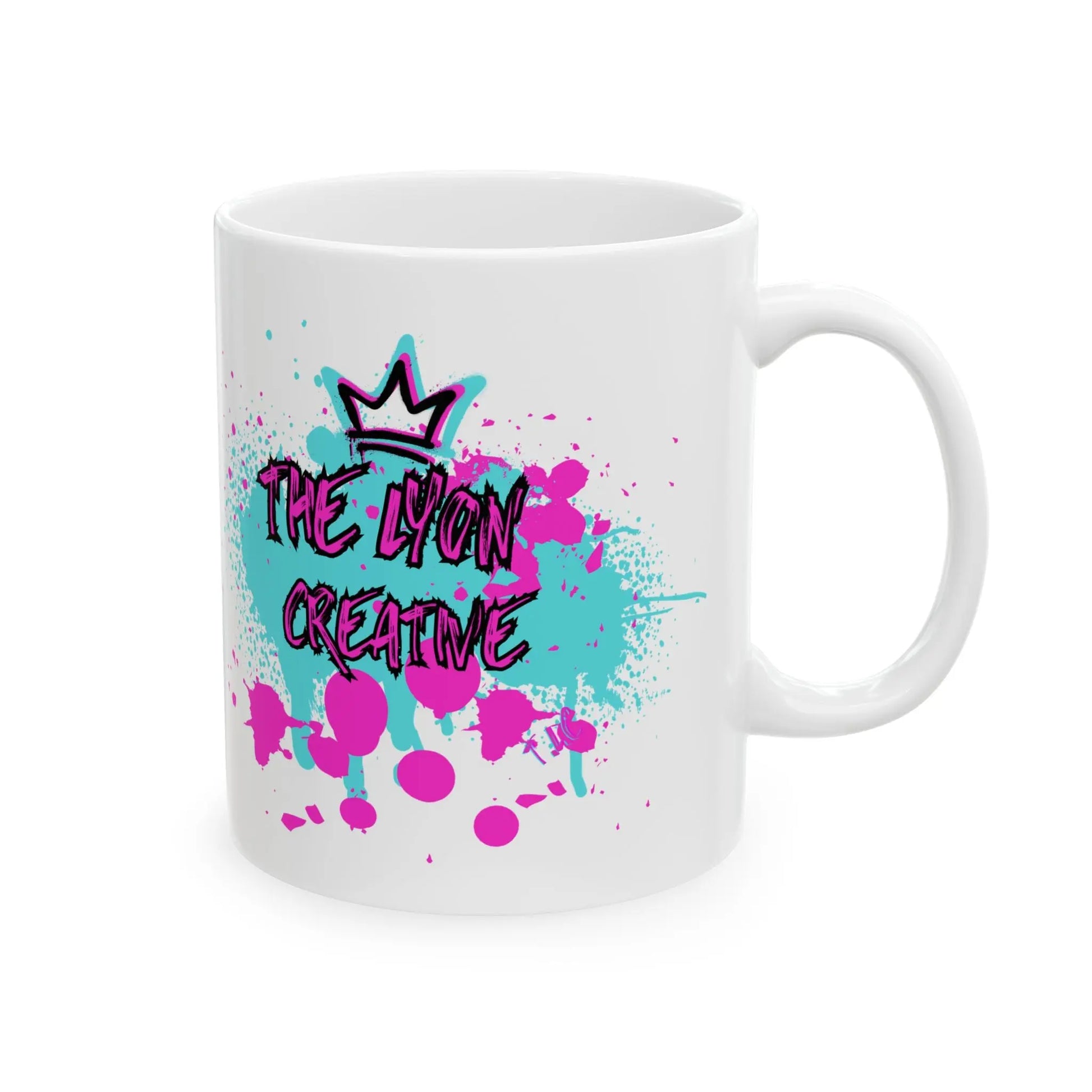 The Lyon Mug, available in 11oz and 15oz sizes, is a sturdy white ceramic mug boasting a vibrant graffiti design. It showcases a crown above black text reading "The Lyon Creative," all set against an energetic background of pink and teal splatters.