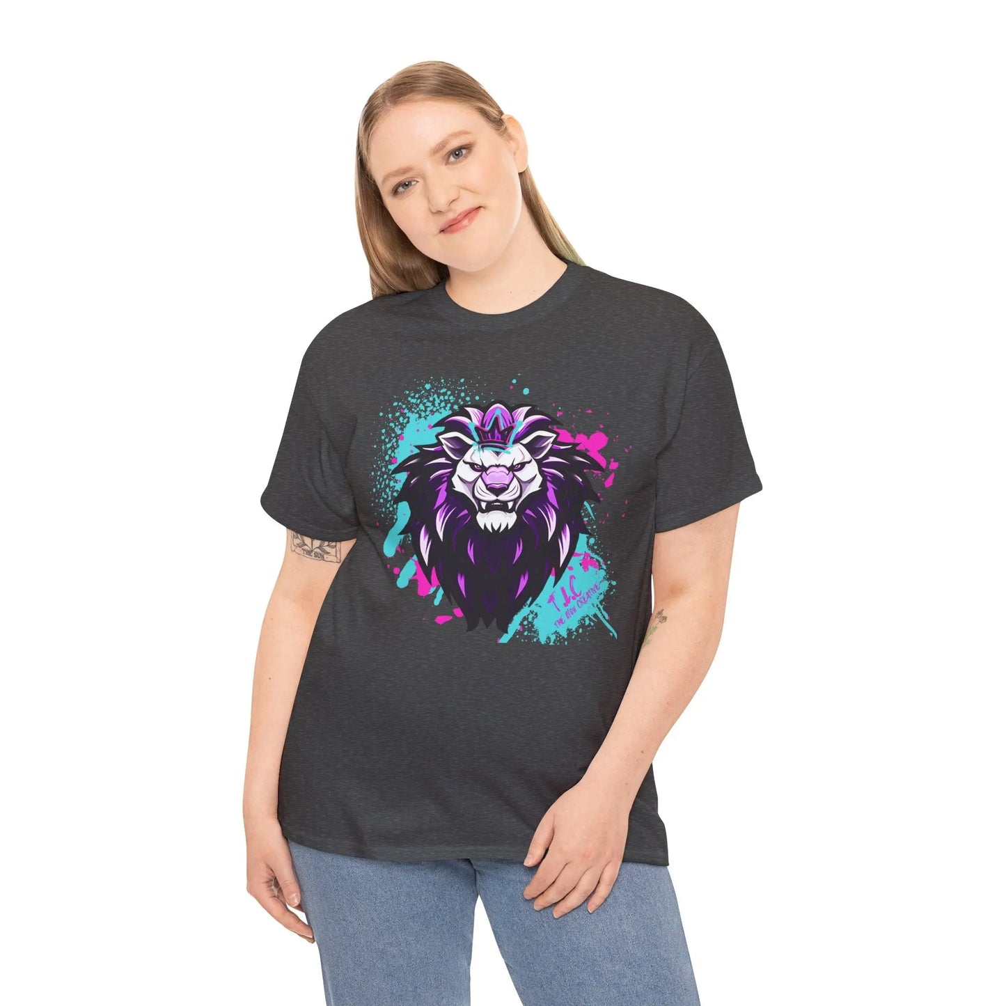 A person with long hair smiles while wearing "The Lyon T-shirt," a dark tee featuring a vibrant, stylized lion illustration in purple and blue. Made from 100% cotton, this classic fit t-shirt stands out against the plain white background.