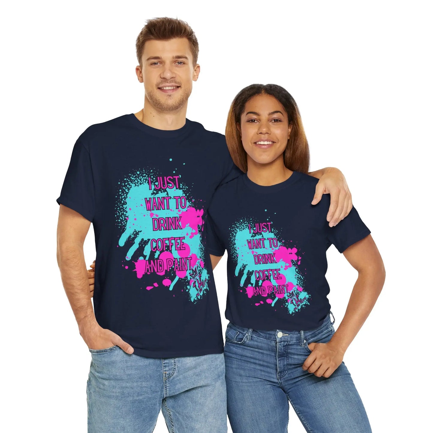 A man and woman stand together, smiling in their classic fit "I Just Want to Drink Coffee" navy blue T-shirts, which are adorned with colorful paint splashes. Made from 100% cotton, the shirts display the phrase, "I just want to drink coffee and paint." He has his arm around her shoulder.