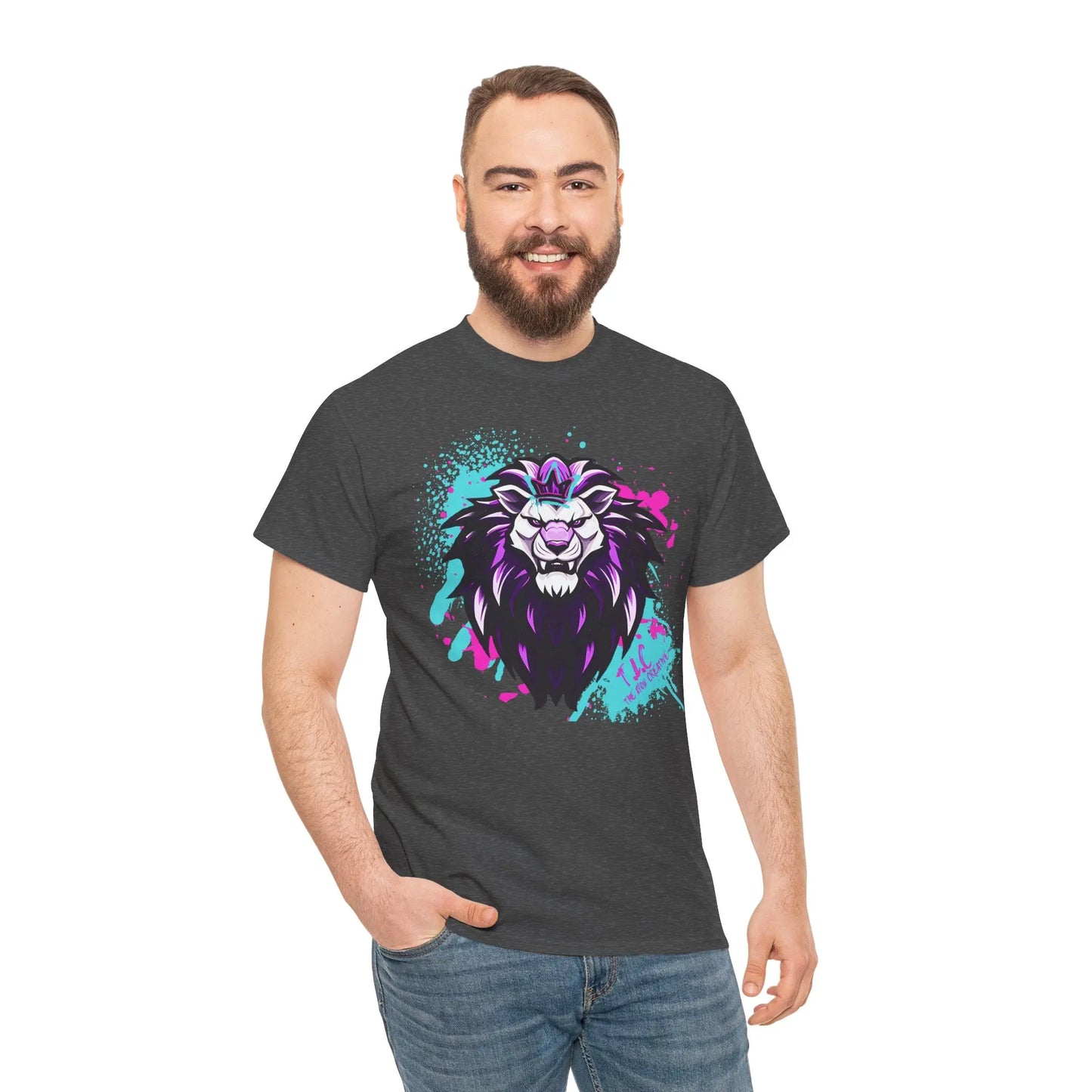 A man with a beard smiles while wearing The Lyon T-shirt, crafted from 100% cotton in dark gray and showcasing a colorful, stylized lion graphic with purple and blue accents. In classic fit, he stands with one hand in his pocket against a plain white background.